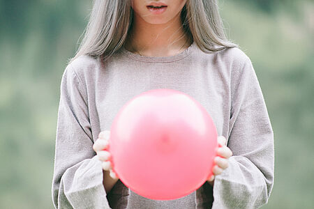 Junge Frau mit einem pinken Luftballon