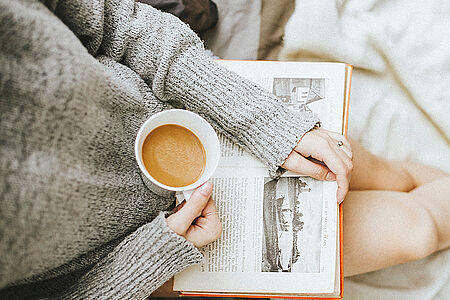 Junge Frau mit einer Tasse Tee und einem Buch